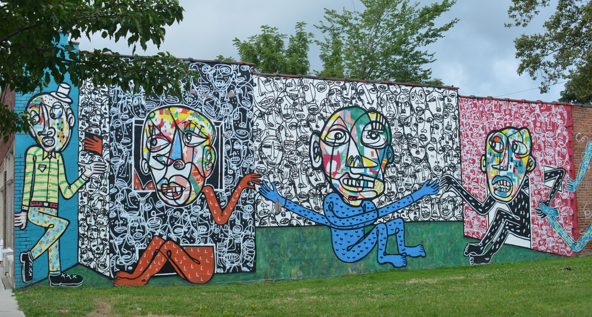 four panels in a a mural of people with large multicoloured faces, blue and red bodies, all holding hands,