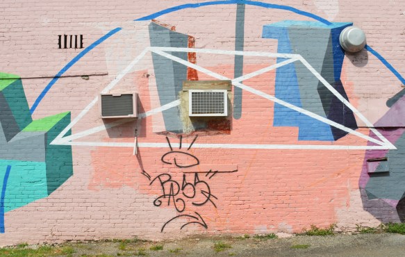 abstract geometric shapes in a mural, pink background, shapes in blues and greys along with some blue and white lines 