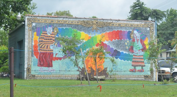 mural on the side of a building, two people facing each other with rainbow coloured lines joining them 