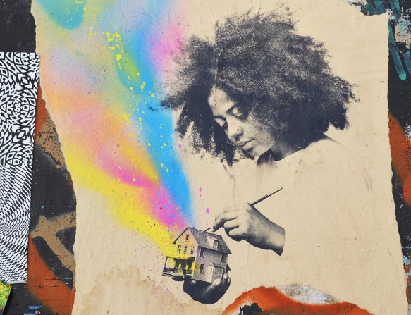 a black girlwith long curly hair is painting a small house, the house is black and white but there is a rainbow of colours coming out of it 