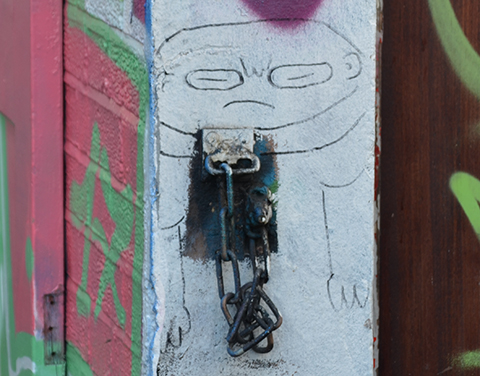 small drawing on a wall, man with scowling face, large head and small body, 
