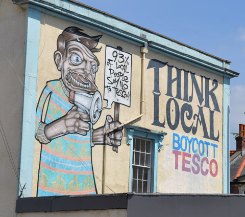 words that say think local boycott tesco, picture of a man holding a protest sign and a megaphone