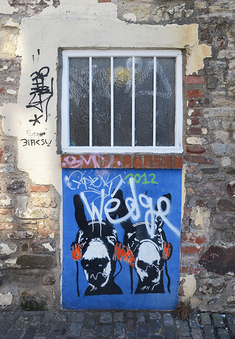 under a barred window, a painting of two faces on blue background