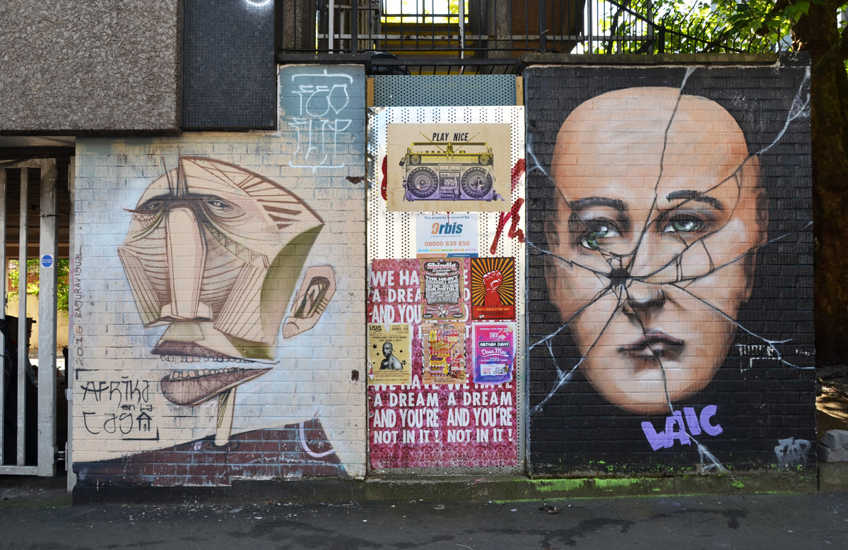 two large faces, one man , one woman, with a door covered with posters between them 