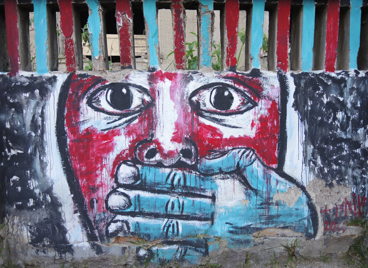 mural in Quito Ecuador , large red face with a blue hand covering its mouth 