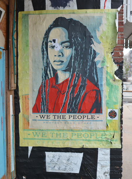 we the people poster featuring a young black woman with long dreadlocks and a red t-shirt 