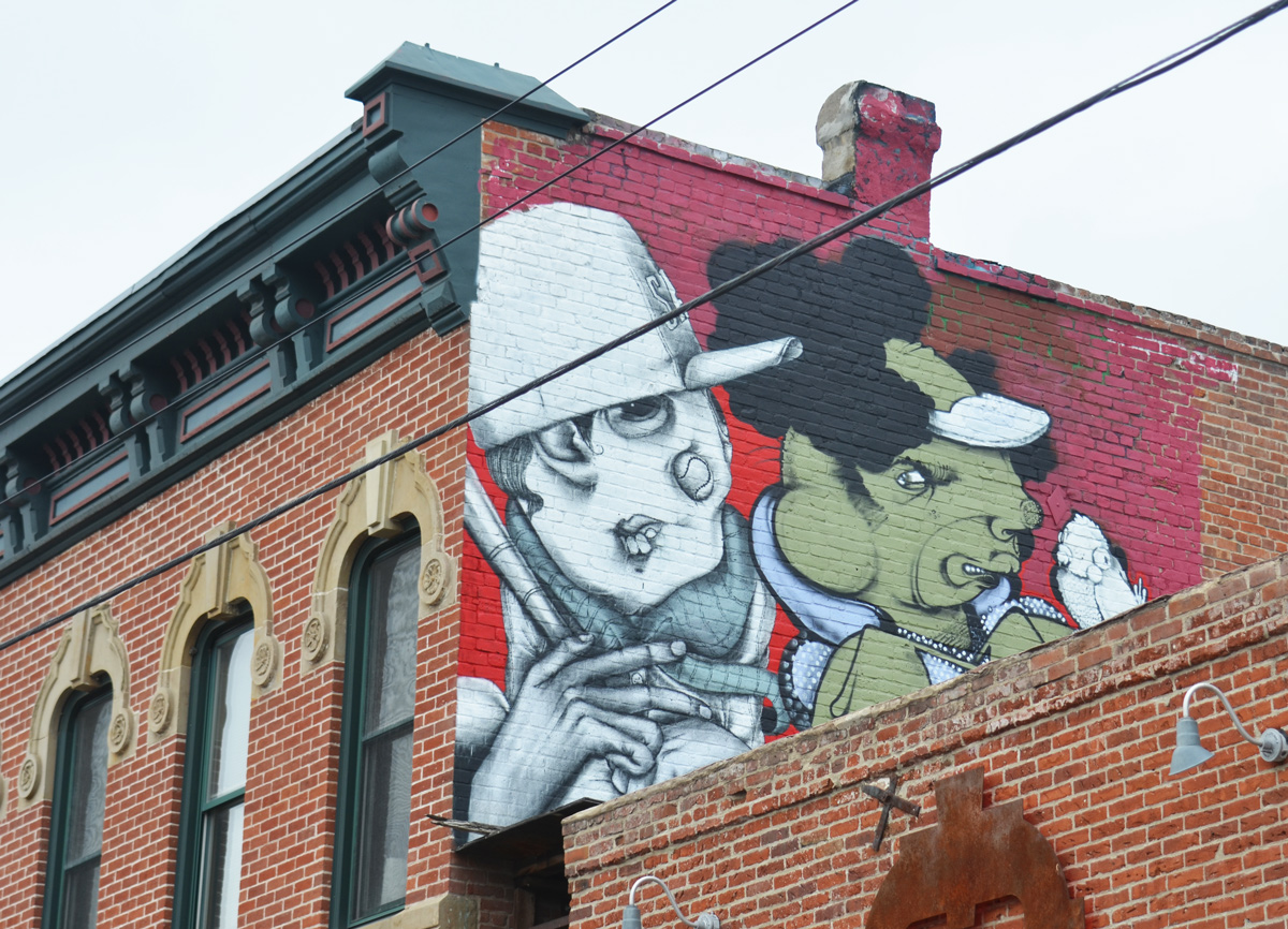 a mural on an upper level of a building, two characters, one white and one green, 