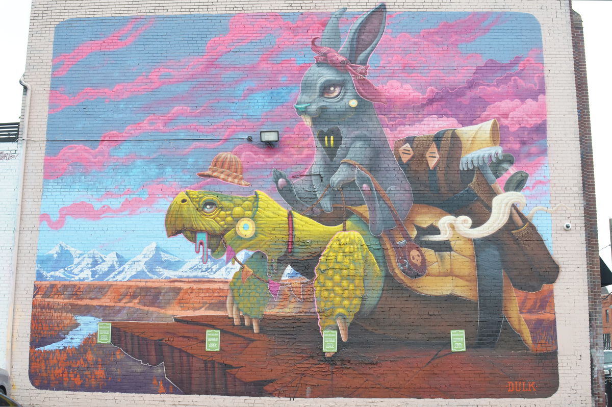 a large mural of a grey rabbit sitting on a green turtle 