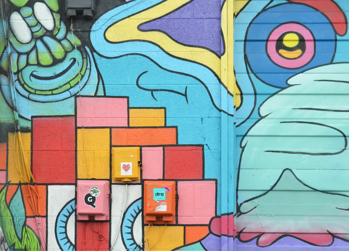 mural in bright colours and abstract shapes, one wringly face, an eye and a nose, some squares, 