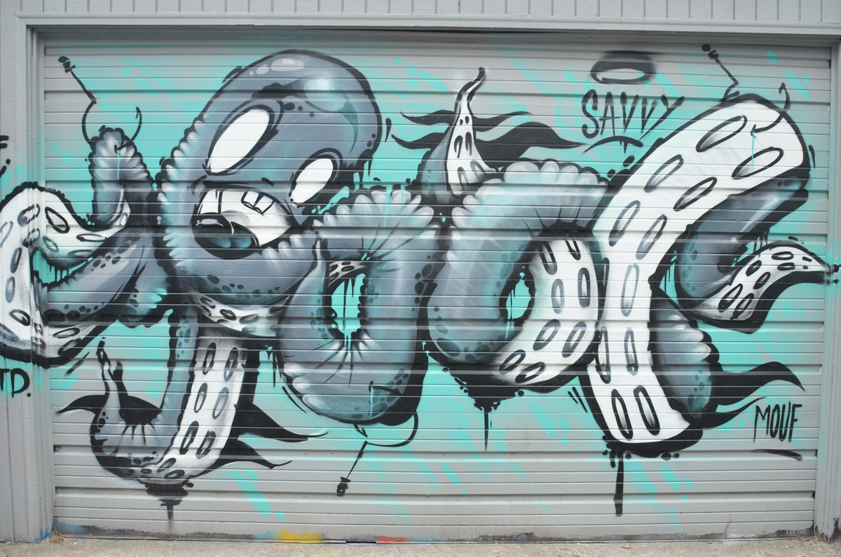 mural on a garage door of a large octopus with its legs all tied up in knots. 