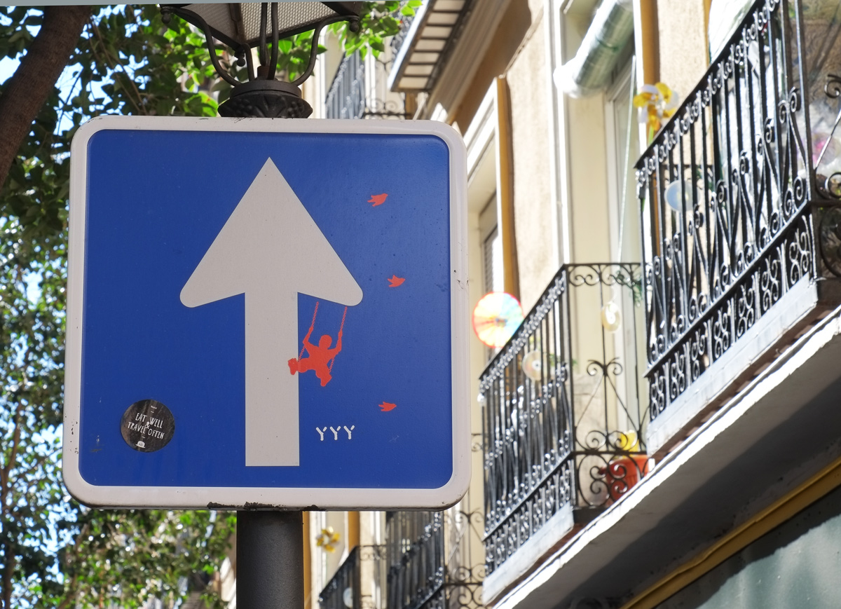 one way sign, arrow is a tree with a pink swing