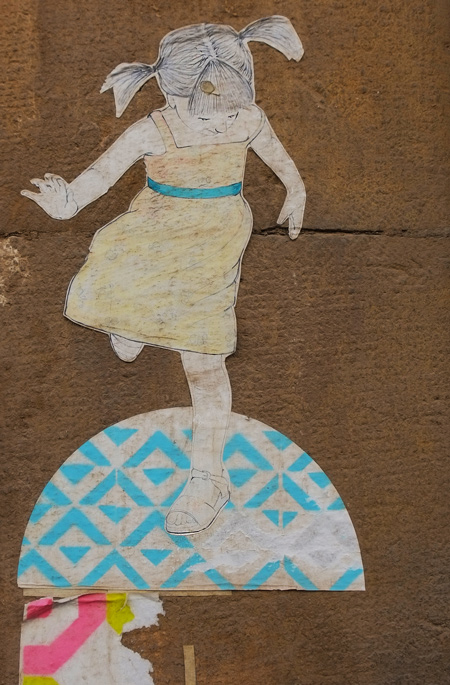 small paper pasteup in pastel colours of a young girl in pigtails hopping on a blue and white semi circle 