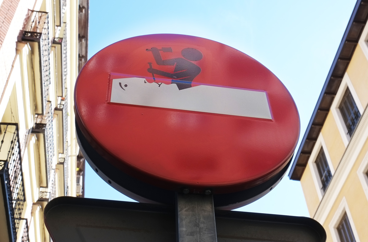 altered do not enter sign,man chiseling out a face from stone, white bar as the block of stone