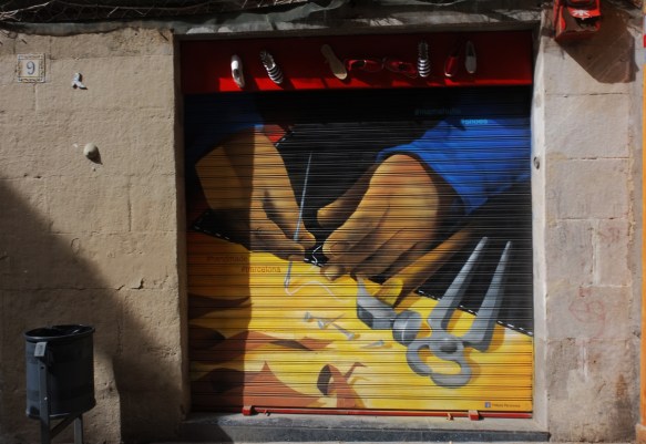 mural on a metal store window covering of a pair of hands working on making shoes 