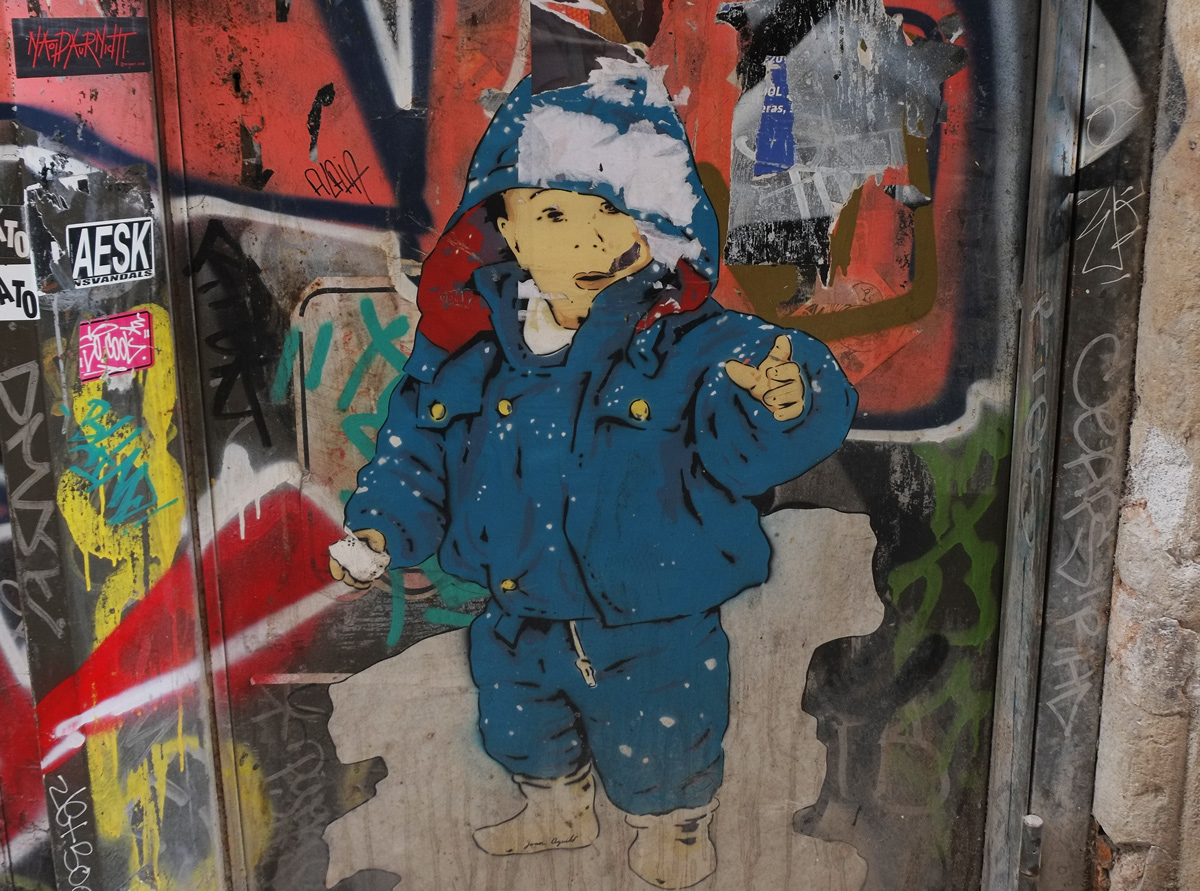 a paste up of a boy in blue snow suit and blue and white hat, he is pointing outwards, 