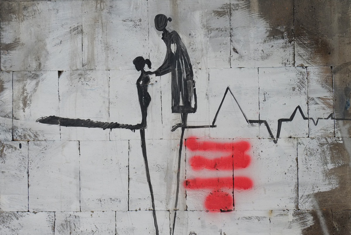mother and daughter figures in black on a wall, mother is guiding daughter forward, standing on lines that are either heart beats or a chasm