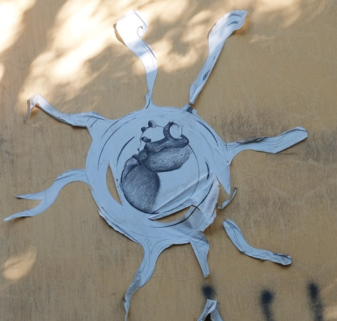 pasteup on a sun shape with long rays, a black and white creature in the center 