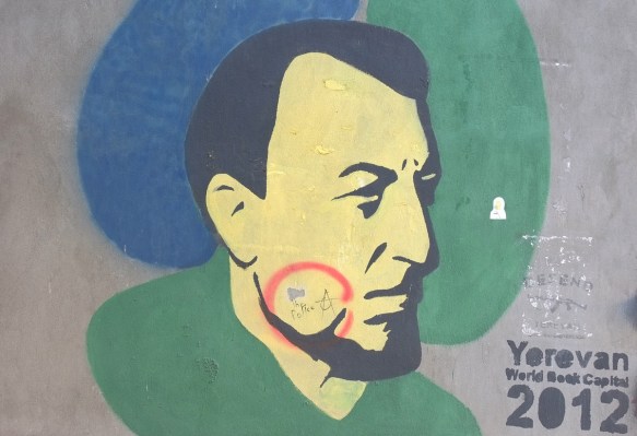 yerevan street art, man's head, in profile, black hair, beard, with yellowish face, words say Yerevan World Book Capital 2012 