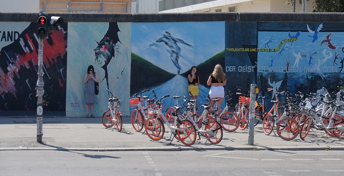 people and parked bikes in front of part of a mural on Berlin Wall, Eastside gallery
