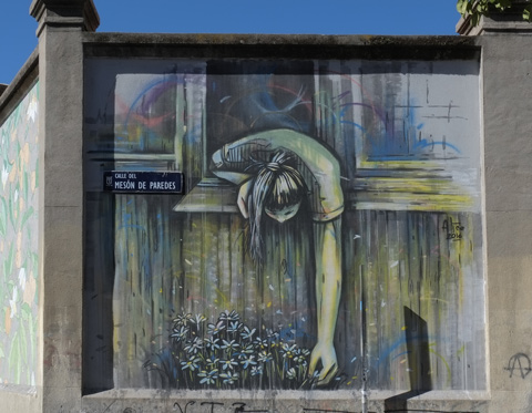 a maural of a woman leaning out a window to pick something growing outside 