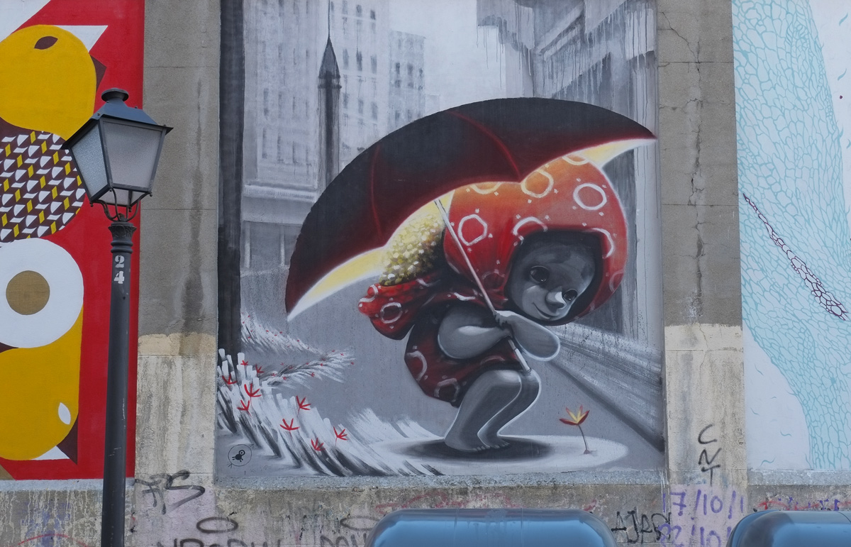 mural of a small girl huddled under an umbrella, grey tone city scape behind her, some small flowers on the ground 
