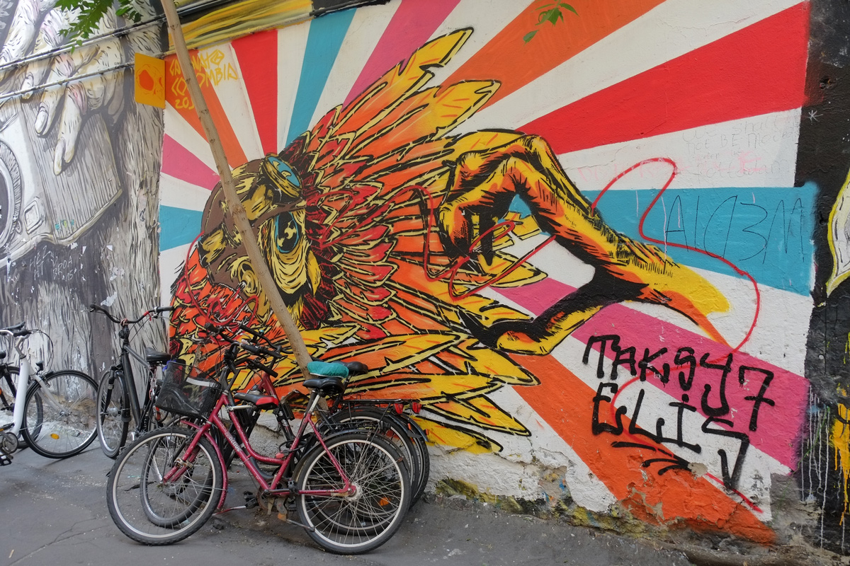 yellow, orange and blue mural of a bird and very large claw reaching for that bird