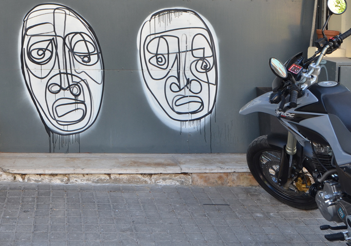 two large white ovals with faces drawn in black lines, one continuous line for each face. A motorbike is also in the picture 