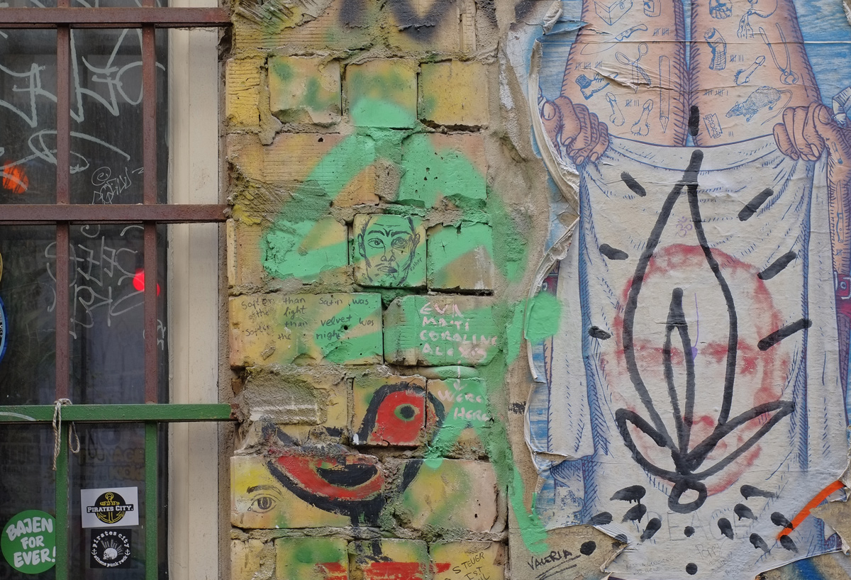 red bird graffiti, green with man's face, brick wall 