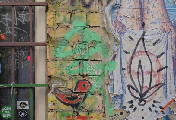 red bird graffiti, green with man's face, brick wall