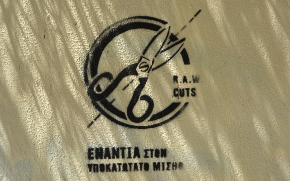 stencil graffiti, circle with a pair of scissors diagonally across it, with words R.A.W. cuts and then some Greek words below it. seen in Athens Greece 