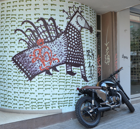 drawing of a horse with its back covered with a blanket, on a wall covered with small green horizontal lines, a motorbike is parked in front of it. 