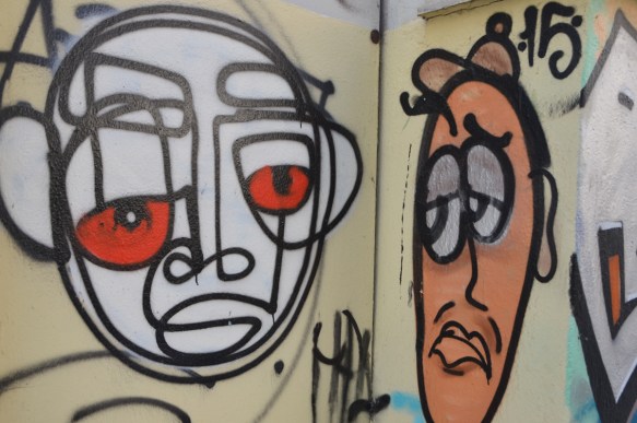 two street art faces, one white and one orange, both with lines drawn in black