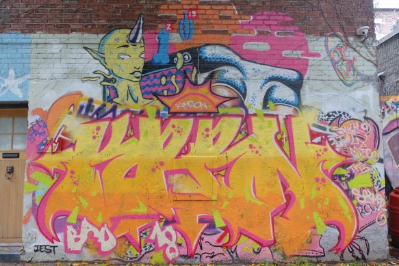 a large mural with a bright yellow and pink tag on the bottom of it, 