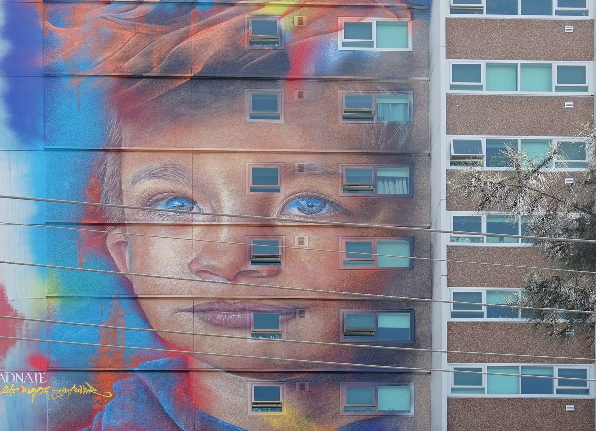 young boy's face in a mural by adnate