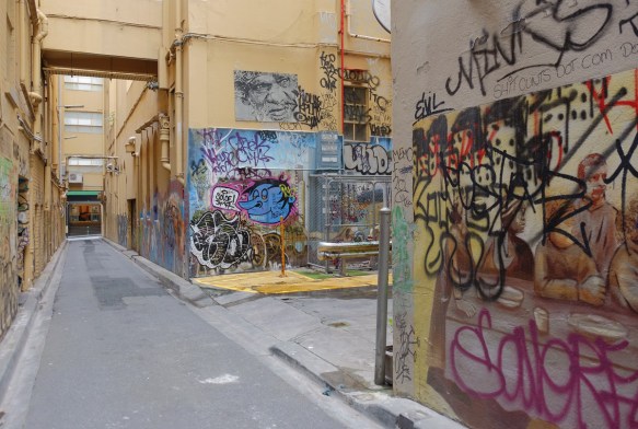 graffiti and street art in an alley, pale yellow walls