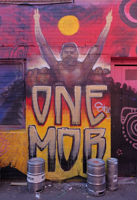 street art painting of a man topless with arms over head in victory, with text underneath that says one mob 