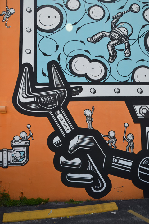 in a mural, a large black wrench that syas adjust on it 