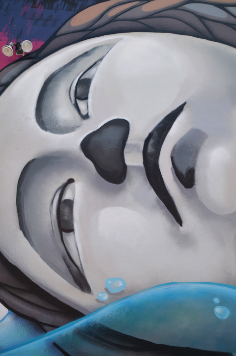 close up of woman's face in mural, in grey tones, lying on her side, width of face is height of wall, blank expression on her face