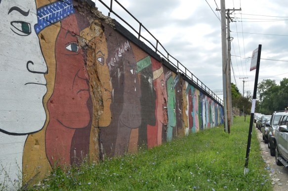 Galeria des barios, a mural of men's faces in profile, different colours, different emotions, 