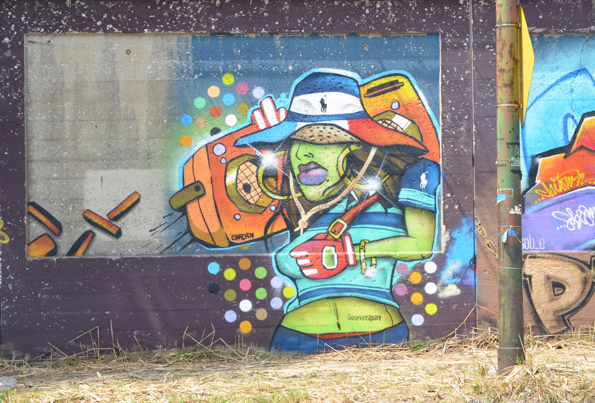 a mural on South Wood Street, a person with a wide brimmed hat carrying a ghetto blaster on her shoulder