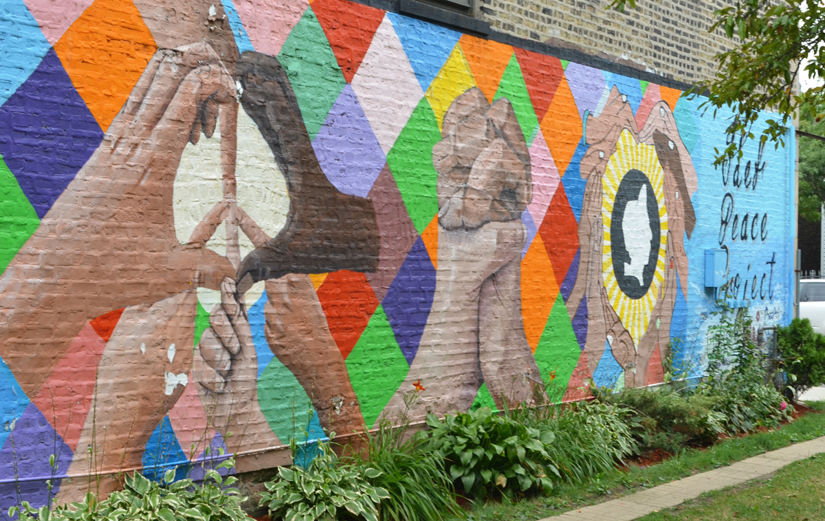 Hands in Unity, a mural featuring large hands in various positions, making heart shapes, making peace symbols, a mural on a wall