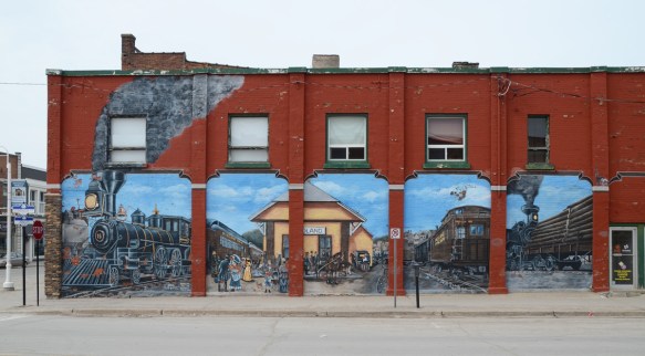 railway mural in Midland Ontario, five panels, train station, two large engines, people, 