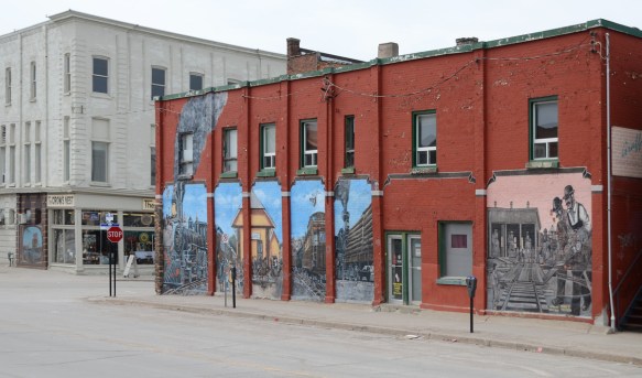 downtown midland ontario, street with reddish brick building, 2 storeys, with a large mural painted on the side