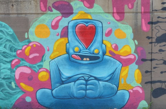 street art painting of a blue man with big square head with a red heart in it 