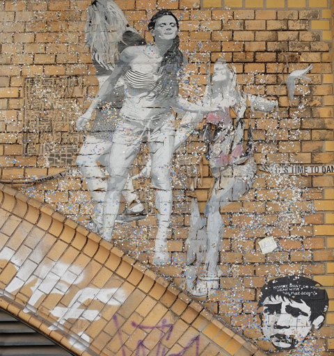 on a brick arch, a paste up in black white, life size picture of people dancing, three women, one with back showing