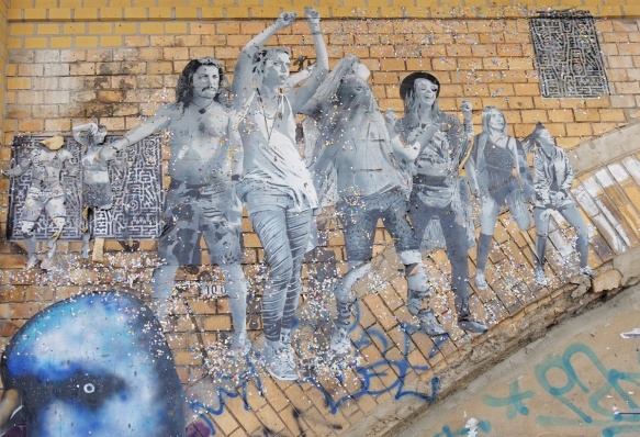 on a brick arch, a paste up in black white, life size picture of people dancing, large group both men and women, glitter too