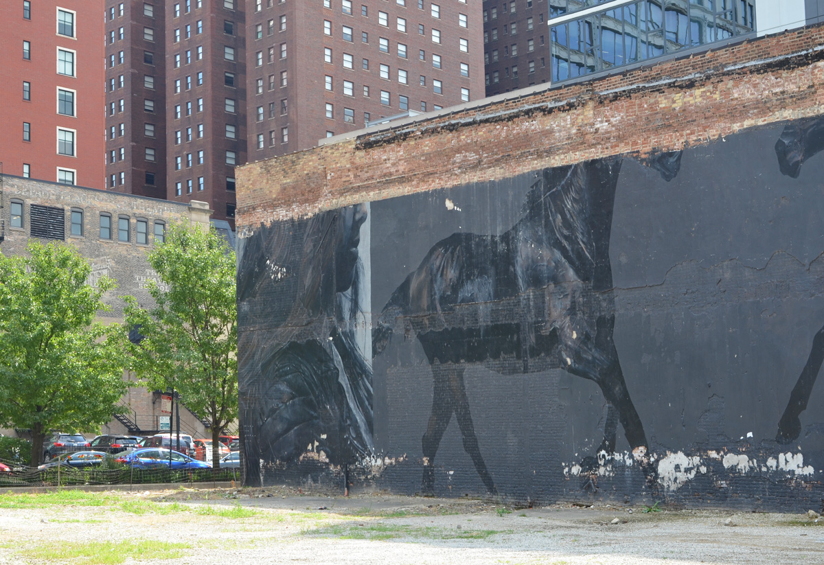 horizontal mural of a woman's head in profile and horses, in black on grey