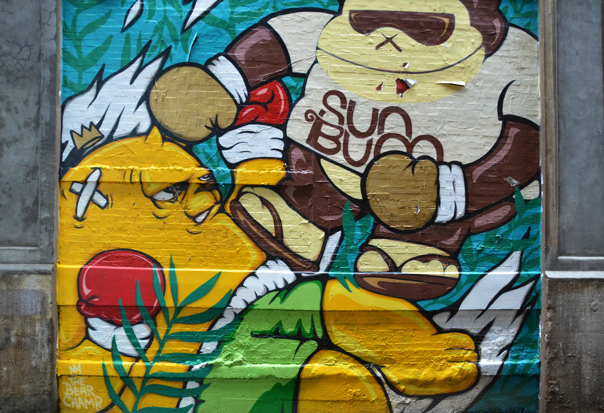 two cartoon-like characters wrestling of boxing, one has shirt on that says sun bum 