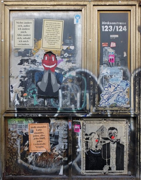 four panes of an old window covered with paste ups and other graffiti. 