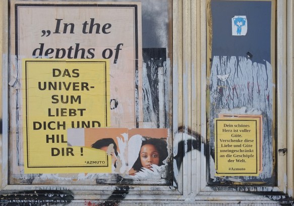 paste ups covering an old window, two posters with words, and one with picture of two black women 